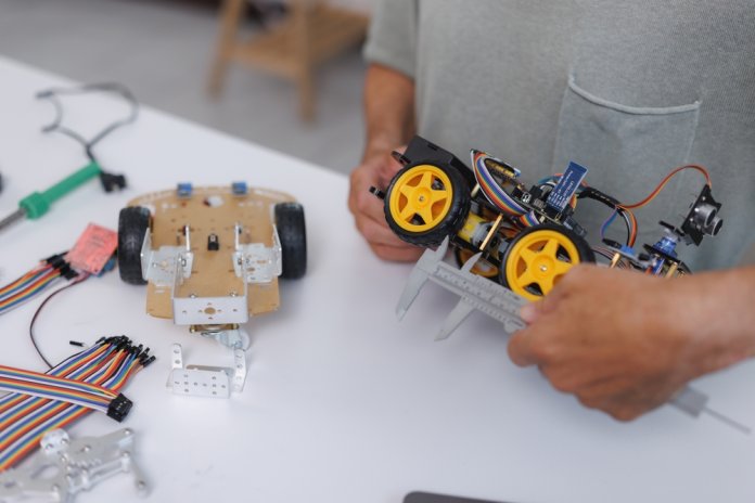 Hands,Measuring,The,Dimensions,Of,A,Small,Robotic,Car,With