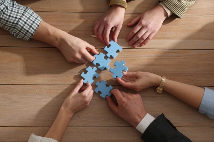 Team,Building.,Group,Of,Businesspeople,Putting,Puzzle,Pieces,Together,At